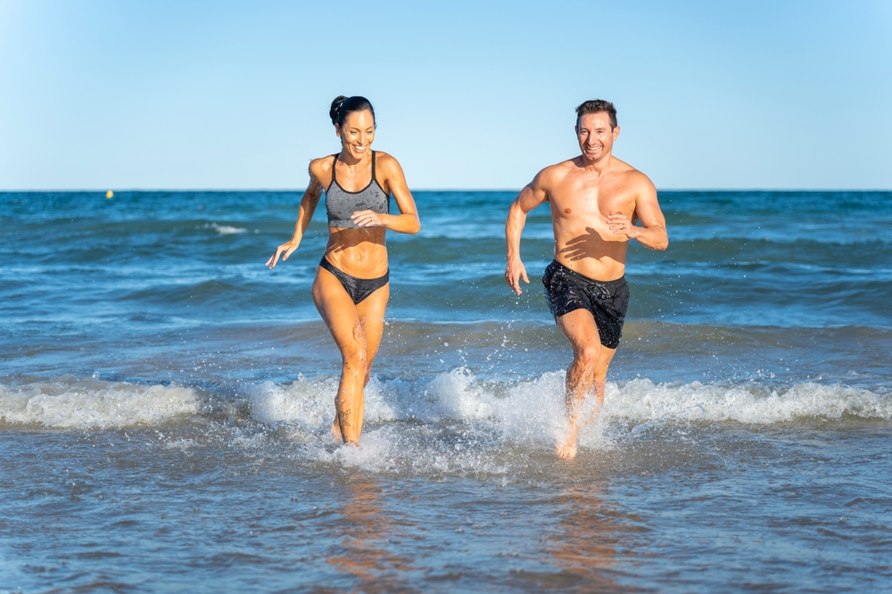 Middle,Aged,Couple,Exercising,Together,On,The,Beach,This,Summer